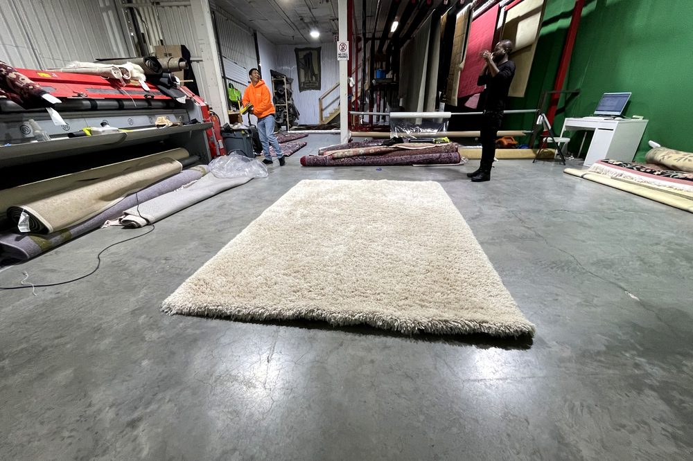 Dr. Carpet18 technician grooming a freshly cleaned wool rug before delivery back to the customer